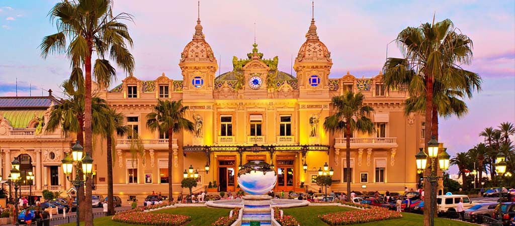 Fényárban úszó Monte Carlo Casino pálmafákkal és szökőkúttal.